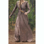 Woman wearing a long brown dress standing in a forest